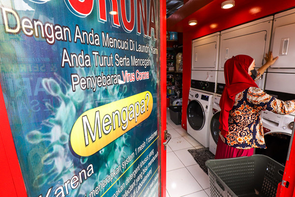Pekerja sedang menyelesaikan pakaian yang akan dicuci di salah satu usaha jasa pencucian pakaian atau laundry di Jakarta Barat, Jumat (23/7/2021).