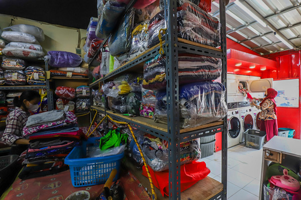 Pekerja sedang menyelesaikan pakaian yang akan dicuci di salah satu usaha jasa pencucian pakaian atau laundry di Jakarta Barat, Jumat (23/7/2021).