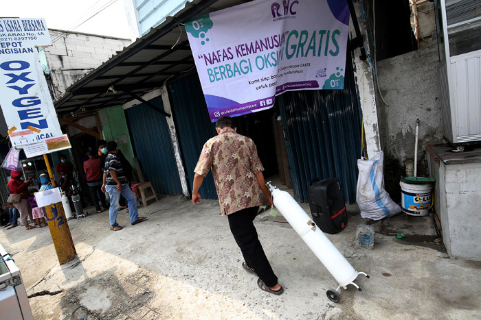 Sejumlah warga antre untuk mendapatkan isi ulang oksigen medis yang dibagikan secara gratis di Jalan Minangkabau Timur, Jakarta, Jumat (23/7/2021).
