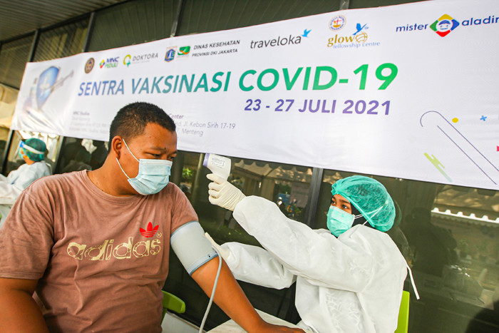 Petugas saat memberikan suntikan vaksin Covid-19 jenis Sinovac untuk warga di Sentra Vaksinasi MNC Center, Kebon Sirih, Jakarta Pusat, Minggu (25/7/2021).