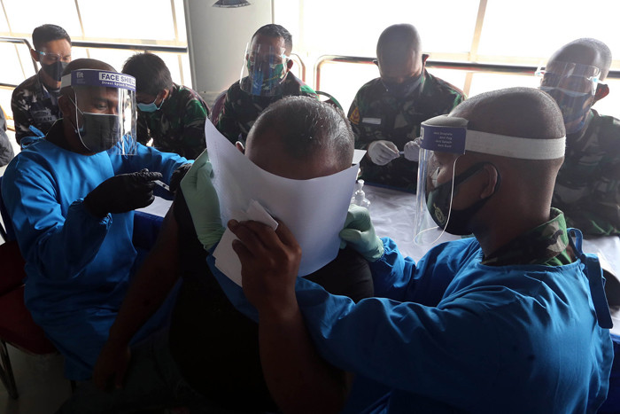 Peserta vaksin menutup muka ketika mendapat suntikan vaksin Covid-19 dalam serbuan vaksin masyarakat maritim di Gedung GSN, Jawa Timur, Senin (26/7/2021).