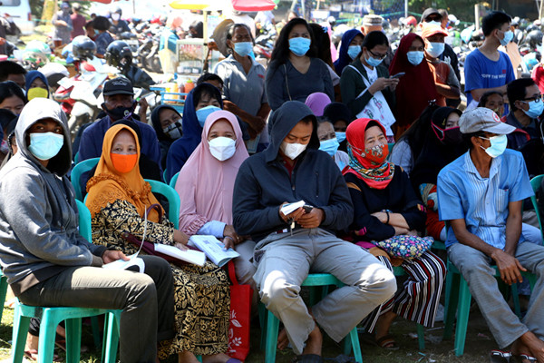 Suasana antrean pengambilan Bantuan Sosial Tunai (BST) di Lapangan Pacar Keling, Surabaya, Jawa Timur, Selasa (27/7/2021).