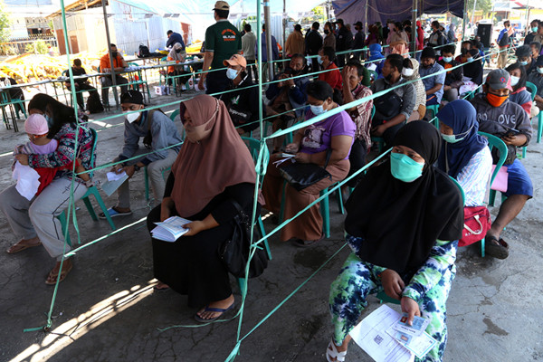 Suasana antrean pengambilan Bantuan Sosial Tunai (BST) di Lapangan Pacar Keling, Surabaya, Jawa Timur, Selasa (27/7/2021).