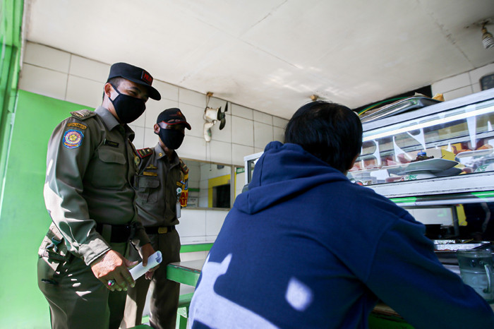 Petugas Satpol PP bersama TNI dan Polisi memberikan sosialisasi kepada pemilik rumah makan di kawasan Margonda, Depok, Jawa Barat, Rabu (28/7/2021).