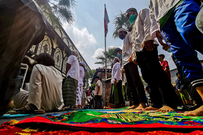 Jamaah saat menjalankan shalat jumat dengan protokol kesehatan di luar lingkungan masjid dikarenakan pembatasan kapasitas di Jakarta Barat, Jumat (30/7/2021).
