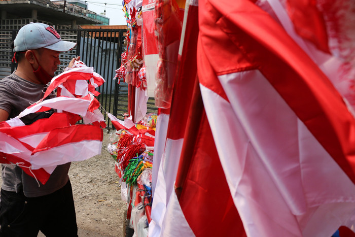 Penjual bendera merah putih dan pernak-pernik HUT Kemerdekaan Republik Indonesia yang Ke-76 merapikan dagangannya di Jalan Matraman, Jakarta (31/7/2021).