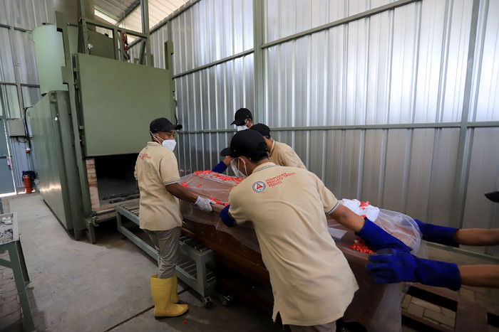 Petugas krematorium bersama keluarga duka mengangkat peti jenazah Covid-19 untuk dikremasi di TPU Tegal Alur, Jakarta, Sabtu (31/7/2021).