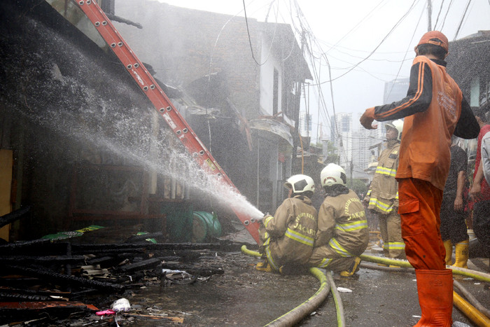 Petugas pemadam kebakaran melakukan pendinginan terhadap bangunan yang terbakar di Jalan Karet Pasar Baru, Karet Tengsin, Jakarta Pusat, Sabtu (31/7/2021).