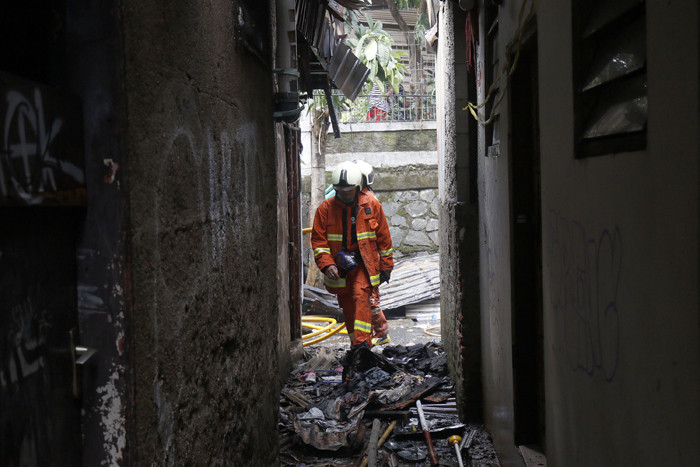 Petugas pemadam kebakaran melakukan pendinginan terhadap bangunan yang terbakar di Jalan Karet Pasar Baru, Karet Tengsin, Jakarta Pusat, Sabtu (31/7/2021).
