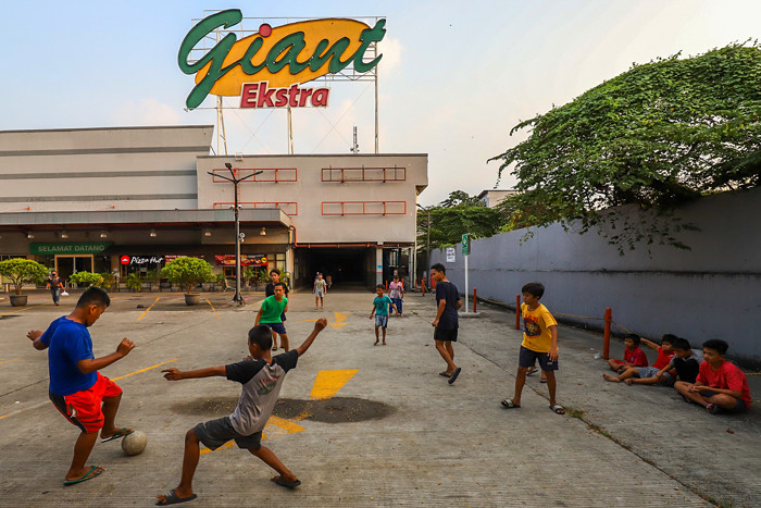 Anak-anak bermain bola di depan gedung gerai Giant yang resmi tutup, di kawasan, Tangerang, Banten, Senin (2/8/2021).