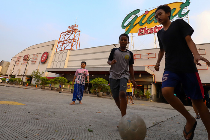 Anak-anak bermain bola di depan gedung gerai Giant yang resmi tutup, di kawasan, Tangerang, Banten, Senin (2/8/2021).