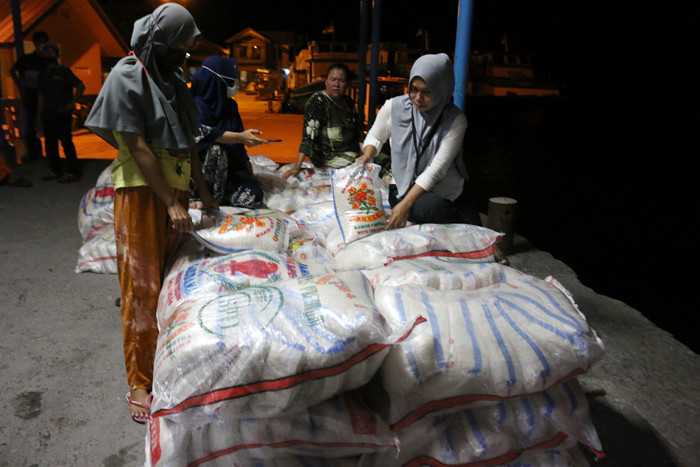 Warga membantu bongkar muat beras bantuan sosial yang tiba di Dermaga Pelabuhan Pulau Panggang, Kepulauan Seribu Utara, Provinsi DKI Jakarta, Selasa (3/8/2021).
