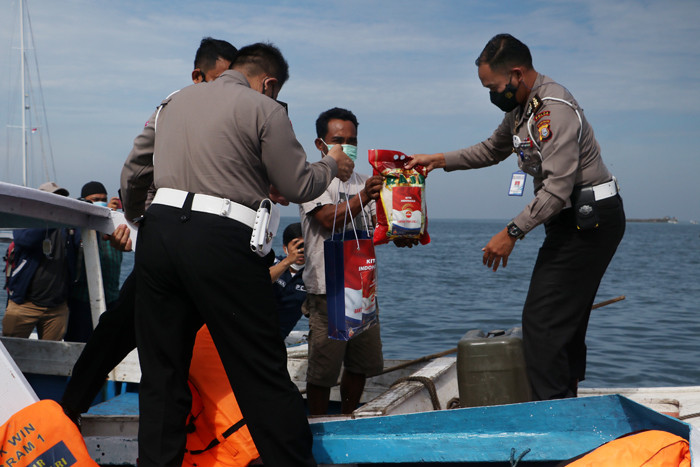 Petugas kepolisian Direktorat Lalulintas Polda Sulsel membagikan paket bantuan sembako pada warga pulau Lae Lae, Makassar, Jumat (6/8/2021).