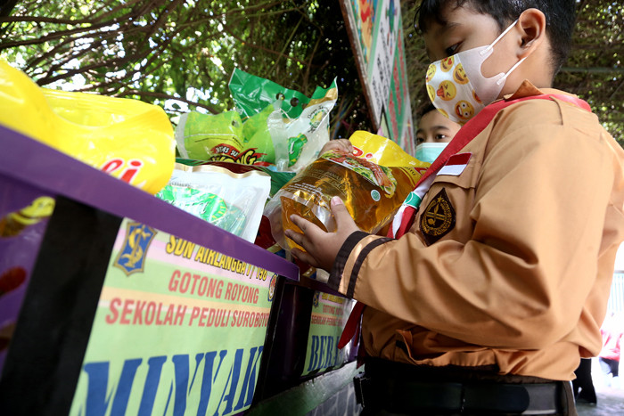 Sejumlah siswa dan walimurid meletakkan donasi berupa kebutuhan pokok di depan gerbang sekolah SD Negeri 1 Airlangga, Surabaya, Jawa Timur, Jumat (6/8/2021).