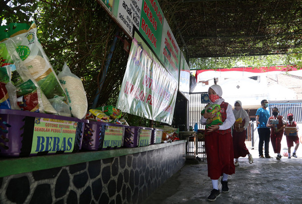 Sejumlah siswa dan walimurid meletakkan donasi berupa kebutuhan pokok di depan gerbang sekolah SD Negeri 1 Airlangga, Surabaya, Jawa Timur, Jumat (6/8/2021).