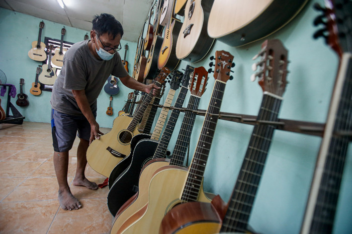 Pekerja menyelesaikan pembuatan gitar di sentra produksi dan reparasi gitar Pak Manto di Pejaten Timur, Pasar Minggu, Sabtu (7/8/2021).