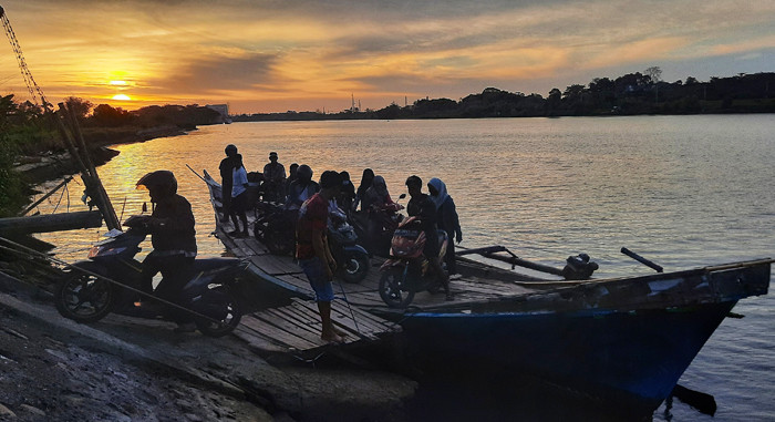 Warga menggunakan perahu penyebrangan di Sungai Jeneberang yang berbatasan langsung Kabupaten Gowa dan Makassar, Minggu (8/8/2021).
