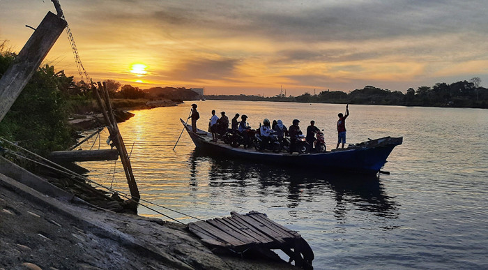 Warga menggunakan perahu penyebrangan di Sungai Jeneberang yang berbatasan langsung Kabupaten Gowa dan Makassar, Minggu (8/8/2021).