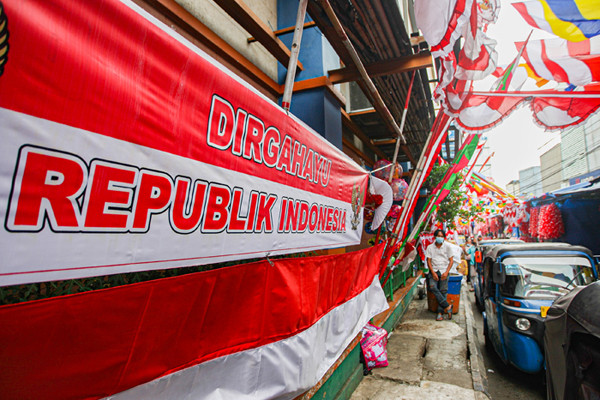 Pedagang melayani pembeli bendera merah putih di Pasar Jatinegara, Jakarta Timur, Senin (9/8/2021).
