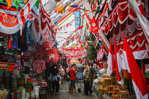 Pedagang melayani pembeli bendera merah putih di Pasar Jatinegara, Jakarta Timur, Senin (9/8/2021).