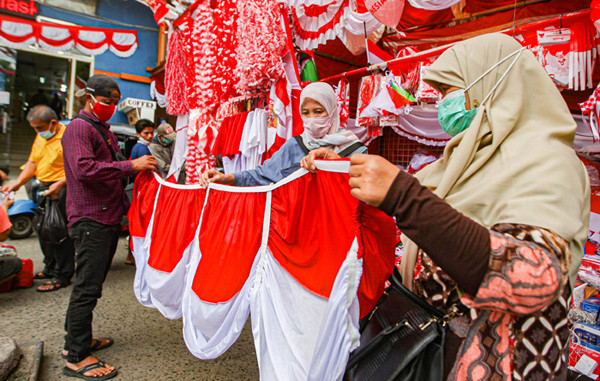 Pedagang melayani pembeli bendera merah putih di Pasar Jatinegara, Jakarta Timur, Senin (9/8/2021).