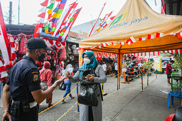 Pengunjung menunjukan sertifikat bukti telah melakukan vaksin kepada petugas sebelum masuk ke Gedung Pasar Jatinegara, Jakarta Timur, Senin (9/8/2021).