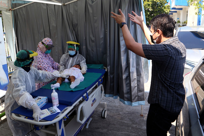 Dokter Spesialis Anak dr. Dini Adityarini memberikan vaksin pada anak ketika melayani vaksinasi secara drive thru di RS Kendangsari Merr, Selasa (10/8/2021).