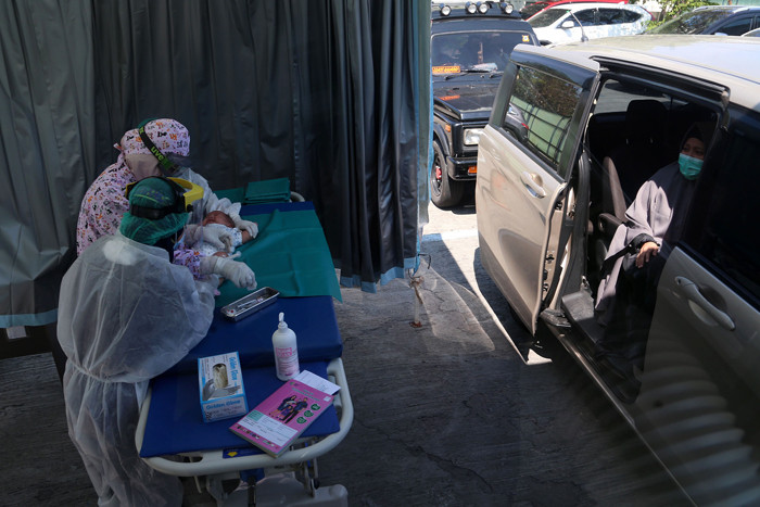 Dokter Spesialis Anak dr. Dini Adityarini memberikan vaksin pada anak ketika melayani vaksinasi secara drive thru di RS Kendangsari Merr, Selasa (10/8/2021).
