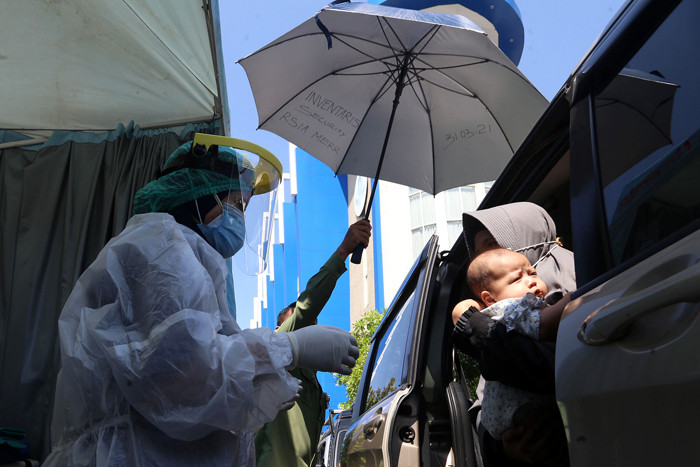 Dokter Spesialis Anak dr. Dini Adityarini memberikan vaksin pada anak ketika melayani vaksinasi secara drive thru di RS Kendangsari Merr, Selasa (10/8/2021).