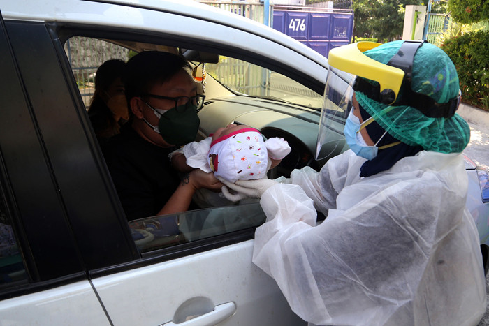 Dokter Spesialis Anak dr. Dini Adityarini memberikan vaksin pada anak ketika melayani vaksinasi secara drive thru di RS Kendangsari Merr, Selasa (10/8/2021).