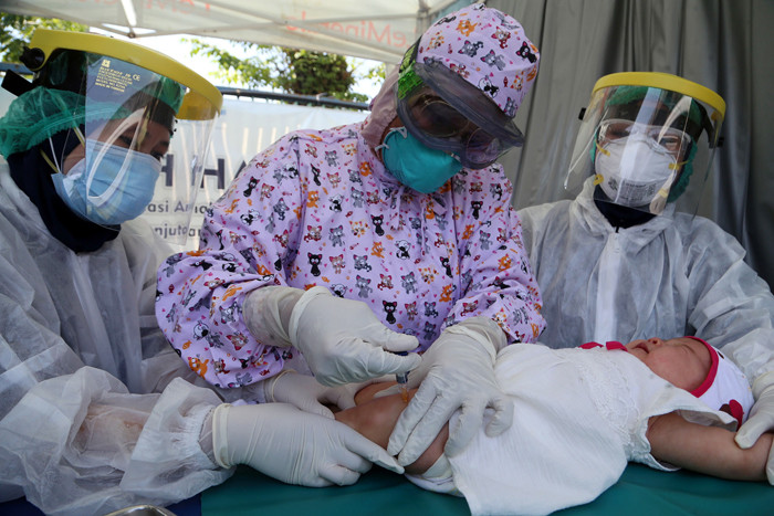 Dokter Spesialis Anak dr. Dini Adityarini memberikan vaksin pada anak ketika melayani vaksinasi secara drive thru di RS Kendangsari Merr, Selasa (10/8/2021).