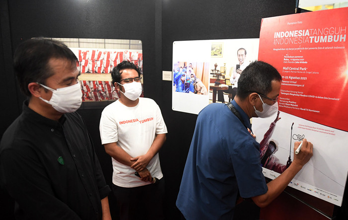 Pengunjung melihat foto yang dipamerkan dalam pameran foto jurnalistik Indonesia Tangguh Indonesia Tumbuh di Mal Central Park, Jakarta, Rabu (11/8/2021).