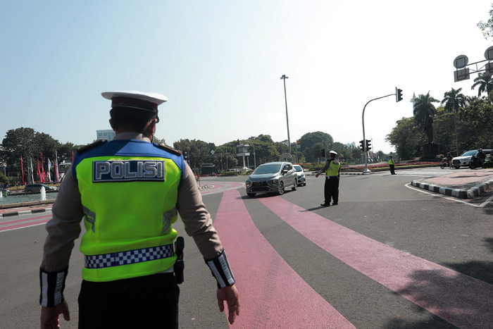 Petugas kepolisian melakukan pengaturan kendaraan saat pelaksanaan pengendalian mobilitas ganjil genap di Jalan MH Thamrin, Jakarta, Kamis (12/8/2021).