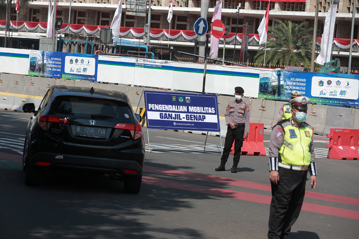 Petugas kepolisian melakukan pengaturan kendaraan saat pelaksanaan pengendalian mobilitas ganjil genap di Jalan MH Thamrin, Jakarta, Kamis (12/8/2021).