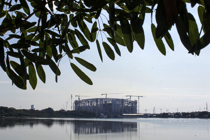 Warga melatih burung merpati dengan latar belakang proyek pembangunan Jakarta International Stadium di Tanjung Priok, Jakarta Utara, Kamis (12/8/2021).