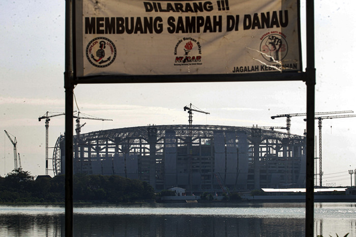 Warga melatih burung merpati dengan latar belakang proyek pembangunan Jakarta International Stadium di Tanjung Priok, Jakarta Utara, Kamis (12/8/2021).