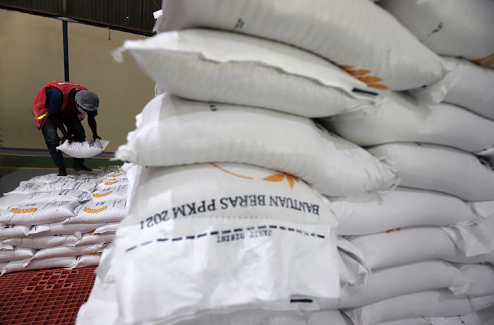 Pekerja mengoperasikan mesin Rice To Rice (RTR) untuk mengisi karung beras bantuan PPKM sebelum didistribusikan ke masyarakat di Jakarta, Jumat (13/8/2021).
