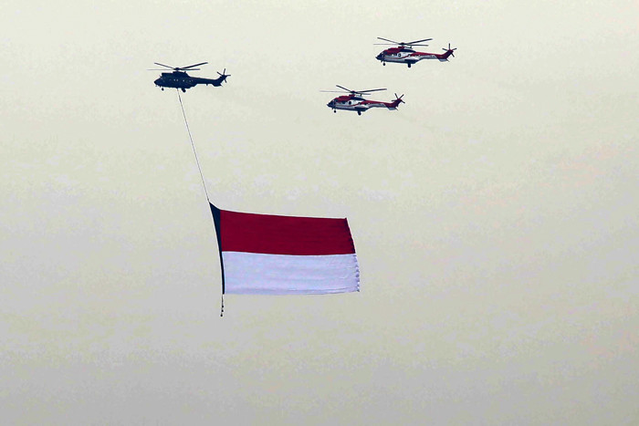 Sejumlah helikopter TNI Angkatan Udara terbang membawa bendera Merah Putih di Jakarta, Jumat (13/8/2021).