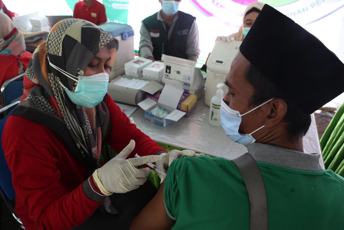 Warga mendapatkan suntikan vaksin Covid-19 ketika mengikuti vaksinasi massal yang dihelat BP Jamsostek di Madura, Jawa Timur, Sabtu (14/8/2021).