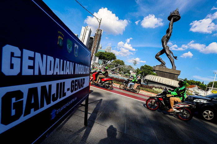 Petugas kepolisian saat mengatur kendaraan yang melintas di Jalan Jenderal Sudirman, Jakarta Pusat, Minggu (15/8/2021).