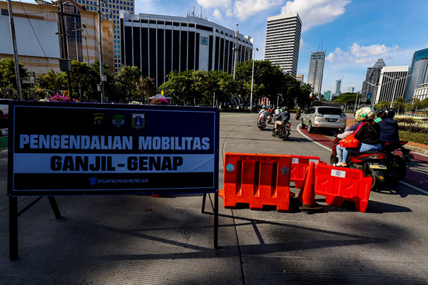Petugas kepolisian saat mengatur kendaraan yang melintas di Jalan Jenderal Sudirman, Jakarta Pusat, Minggu (15/8/2021).