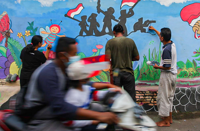 Winy bersama keluarganya saat membuat mural bertema keberagaman budaya Indonesia di Jalan Annur, Lubang Buaya, Jakarta Timur, Minggu (15/8/2021).