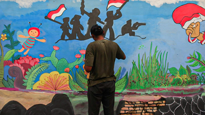 Winy bersama keluarganya saat membuat mural bertema keberagaman budaya Indonesia di Jalan Annur, Lubang Buaya, Jakarta Timur, Minggu (15/8/2021).