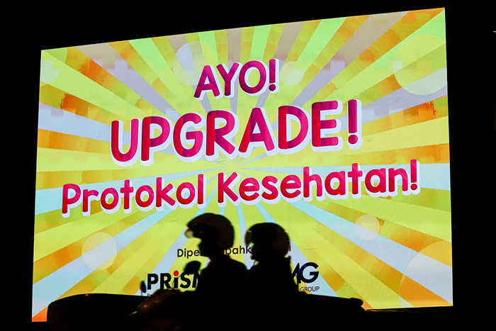Kendaraan saat melintas dengan berlatar belakang himbauan upgrade protokol kesehatan agar rakyat Indonesia merdeka dari covid-19 di Jakarta, Senin (16/8/2021).