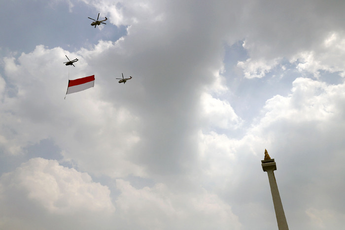Pesawat tempur Angkatan Udara dan Helikopter Angkatan Darat membawa bendera merah putih di kawasan Monumen Nasional (Monas), Jakarta, Selasa (17/8/2021).