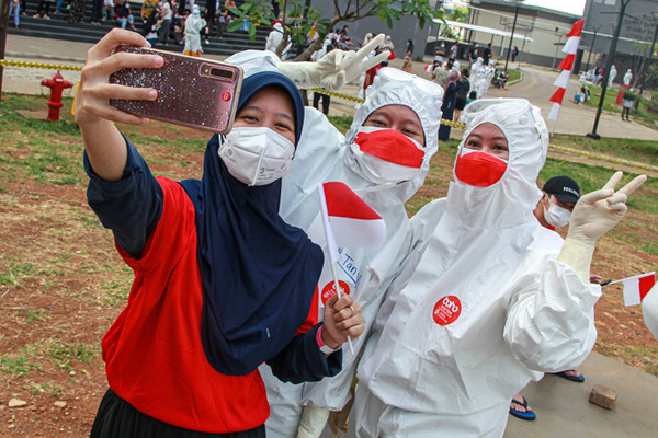 Tenaga kesehatan mengibarkan bendera merah putih saat upacara peringatan kemerdekaan Ke-76 RI di RSDC-19, Wisma Atlet, Jakarta, Selasa (17/8/2021).