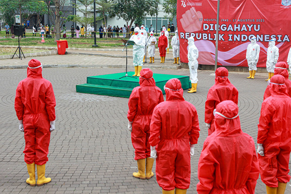 Tenaga kesehatan mengibarkan bendera merah putih saat upacara peringatan kemerdekaan Ke-76 RI di RSDC-19, Wisma Atlet, Jakarta, Selasa (17/8/2021).