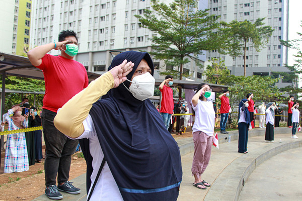 Tenaga kesehatan mengibarkan bendera merah putih saat upacara peringatan kemerdekaan Ke-76 RI di RSDC-19, Wisma Atlet, Jakarta, Selasa (17/8/2021).
