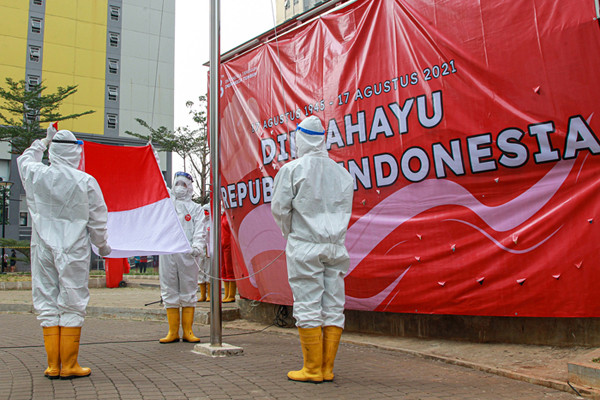 Tenaga kesehatan mengibarkan bendera merah putih saat upacara peringatan kemerdekaan Ke-76 RI di RSDC-19, Wisma Atlet, Jakarta, Selasa (17/8/2021).