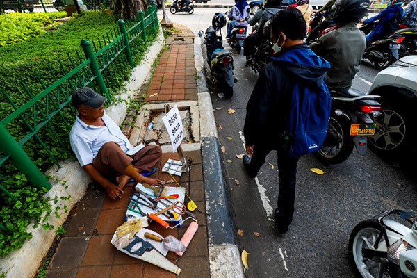 Seorang bapak berprofesi sebagai buruh tukang bangunan menunggu seseorang untuk mengajaknya bekerja di Kawasan Jakarta Pusat, Kamis (19/8/2021).
